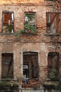 Fachada de un edificio urbano deteriorado con ventanas rotas, ilustrando la teoría de las ventanas rotas
